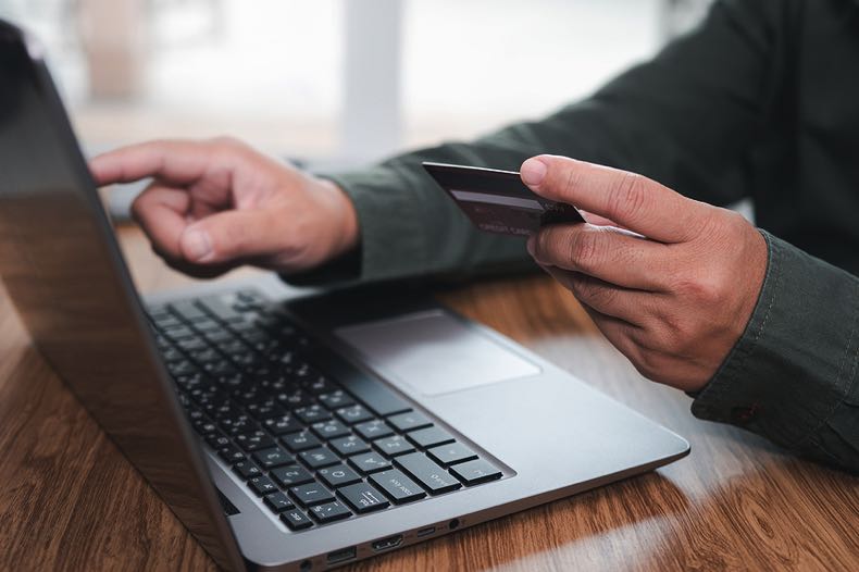 Man holding debit card with laptop